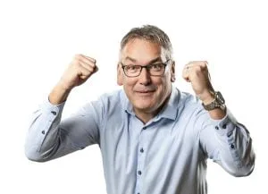 Man in glasses and a blue shirt smiling with fists raised in a celebratory pose against a white background.