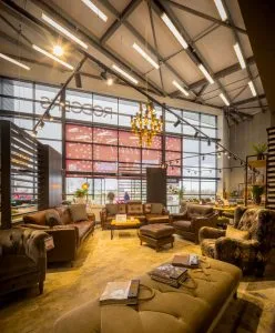 Modern furniture store interior with leather couches, armchairs, a chandelier, large windows, and a prominent "Winter Sale" sign.